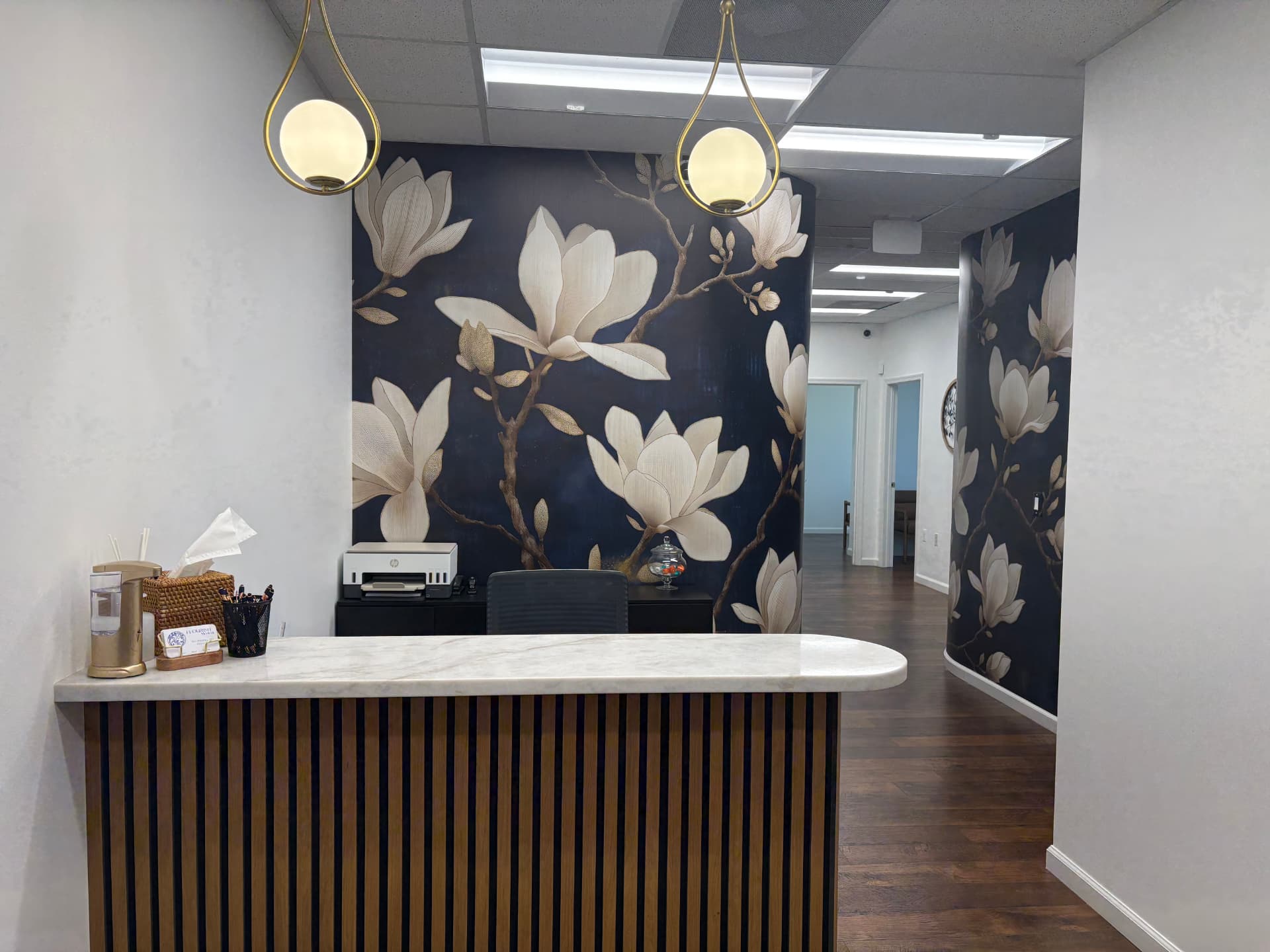 Reception desk at Flourish Medical with magnolia wall covering and brass pendant lights